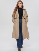 Belted midi trench coat in beige, front view with hands in the pockets.