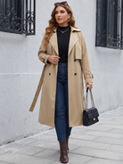 Belted midi trench coat in beige, styled with jeans outdoors.