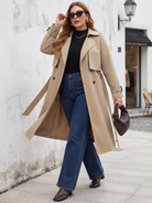 Belted midi trench coat in beige, walking view with jeans.