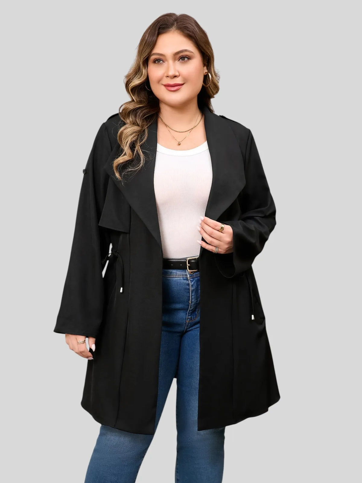 Drawstring-waist trench coat in black, worn open over a top and jeans.