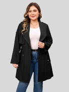 Drawstring-waist trench coat in black, worn open over a top and jeans.
