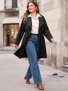 Drawstring-waist trench coat in black, walking view with jeans.